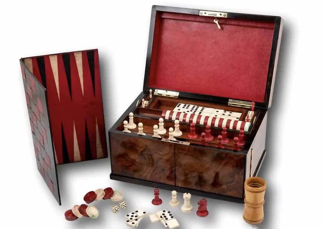 Victoriaanse spellenkoffer met verschillende spellen, waaronder schaakstukken, dobbelstenen, speelkaarten en backgammon